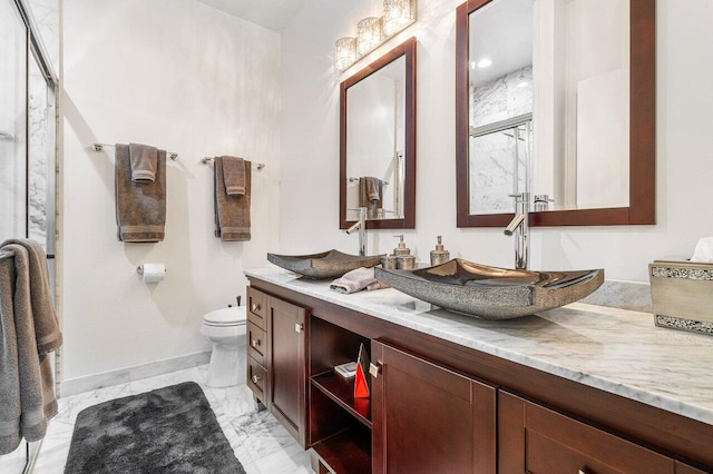 bathroom featuring a shower with shower door, vanity, and toilet