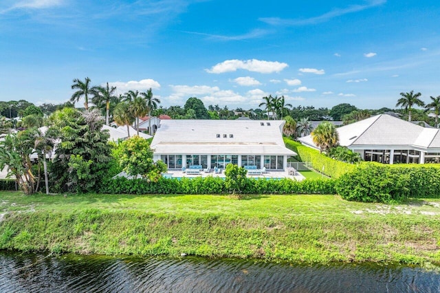 rear view of property with a water view, a patio area, a sunroom, and a lawn