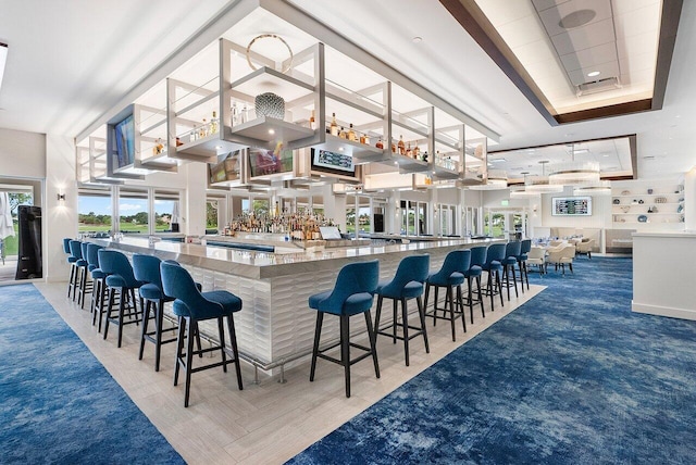 bar featuring a high ceiling, stone counters, and a tray ceiling