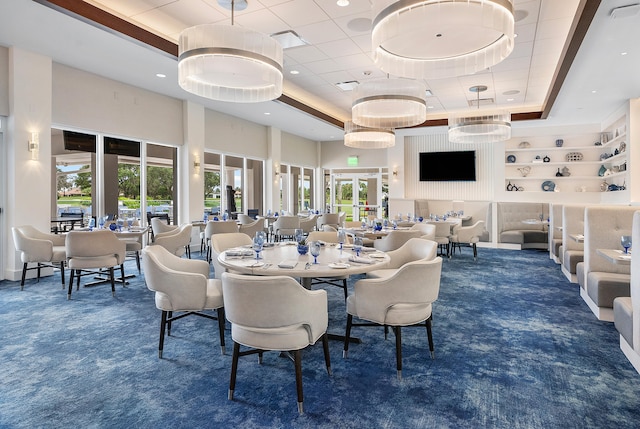 carpeted dining room with a tray ceiling and a towering ceiling