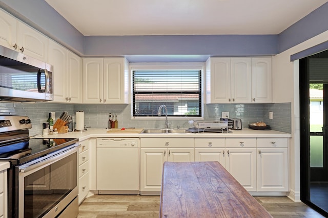 kitchen with white cabinets, light hardwood / wood-style floors, stainless steel appliances, and sink