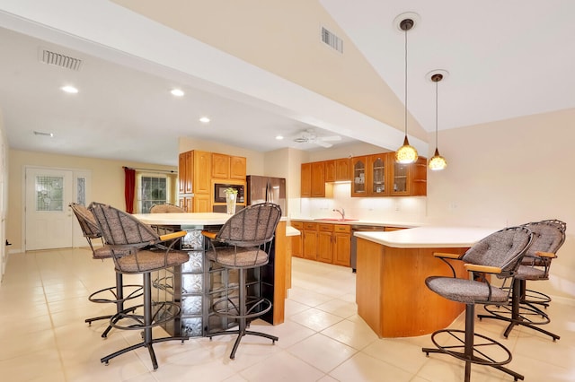 kitchen with vaulted ceiling with beams, appliances with stainless steel finishes, a breakfast bar, sink, and light tile patterned floors