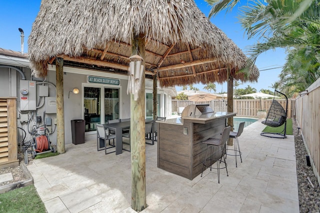 view of patio with water heater, a gazebo, a fenced in pool, and exterior bar