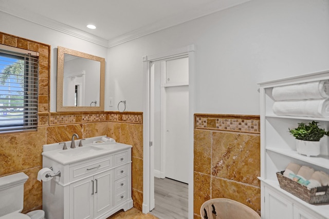 bathroom featuring toilet, vanity, tile walls, hardwood / wood-style floors, and ornamental molding