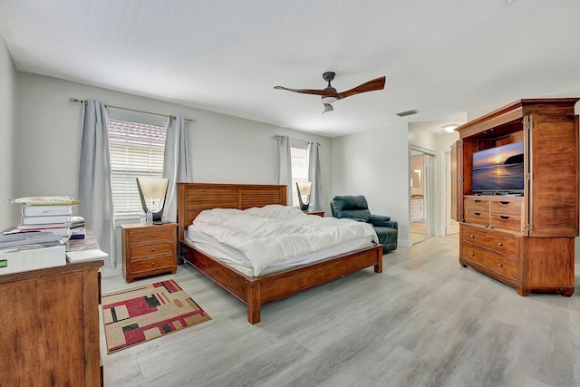 bedroom with multiple windows, ensuite bath, ceiling fan, and light wood-type flooring