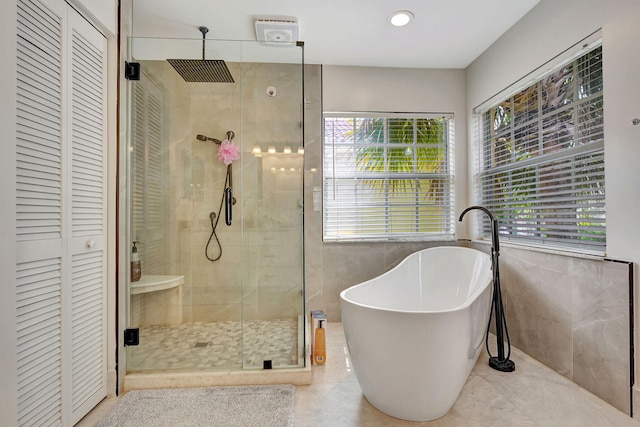 bathroom with tile walls, tile patterned floors, and plus walk in shower