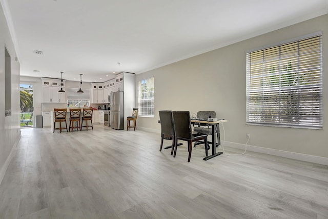 dining space featuring crown molding and light hardwood / wood-style flooring