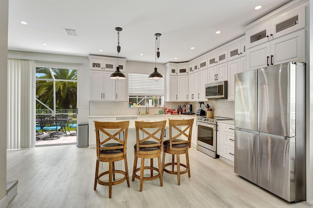 kitchen with a center island, appliances with stainless steel finishes, hanging light fixtures, and decorative backsplash