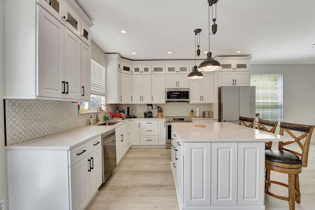 kitchen featuring appliances with stainless steel finishes, a center island, a wealth of natural light, and sink