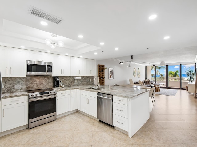 kitchen featuring stainless steel appliances, white cabinetry, sink, and kitchen peninsula