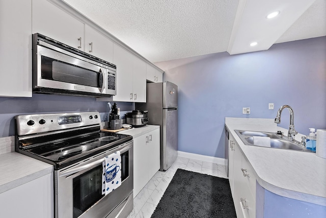 kitchen with white cabinetry, light tile patterned flooring, stainless steel appliances, sink, and a textured ceiling