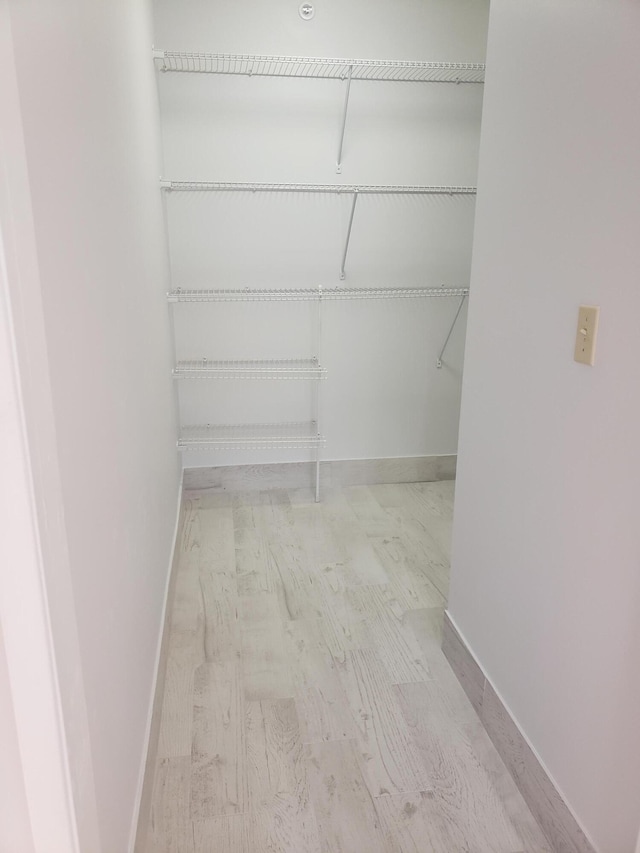 walk in closet with light hardwood / wood-style floors