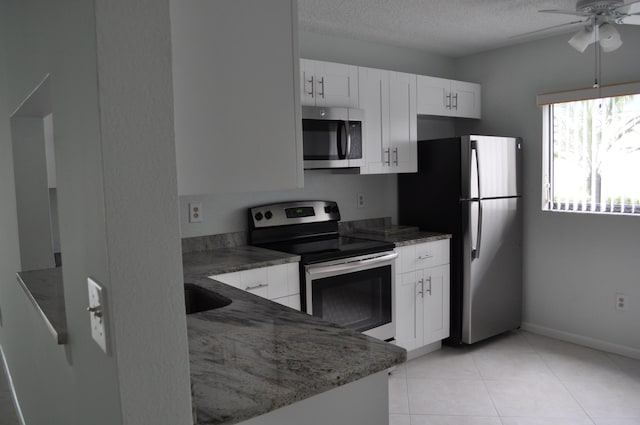 kitchen with stone counters, appliances with stainless steel finishes, a textured ceiling, and white cabinets