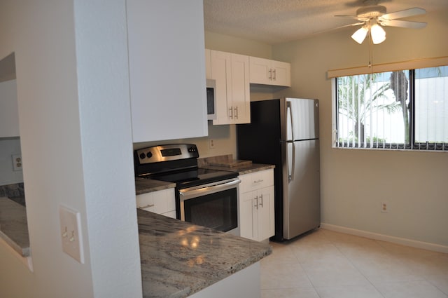 kitchen featuring light tile patterned floors, appliances with stainless steel finishes, dark stone countertops, ceiling fan, and white cabinets