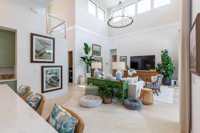 living room with light wood-type flooring, a towering ceiling, and a chandelier