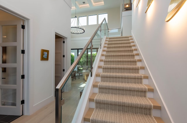 staircase featuring wood-type flooring and an inviting chandelier