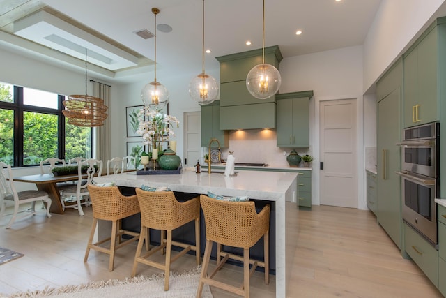 kitchen featuring light hardwood / wood-style floors, double oven, green cabinetry, and backsplash