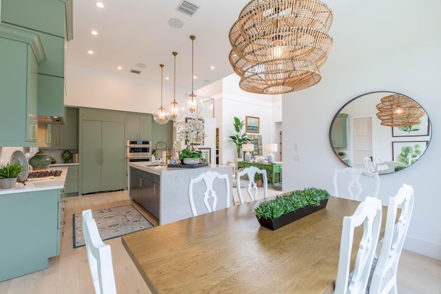 dining space with light hardwood / wood-style floors, a notable chandelier, and sink