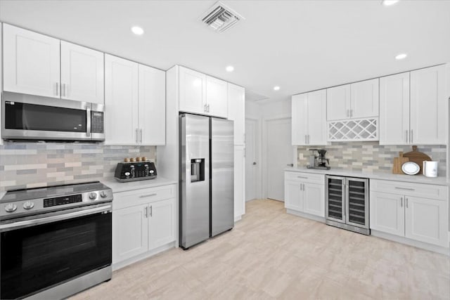 kitchen with stainless steel appliances, wine cooler, and white cabinetry