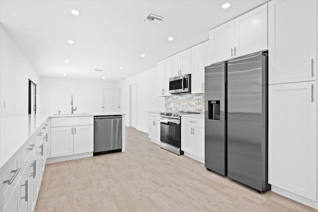 kitchen featuring backsplash, white cabinets, sink, appliances with stainless steel finishes, and light hardwood / wood-style floors