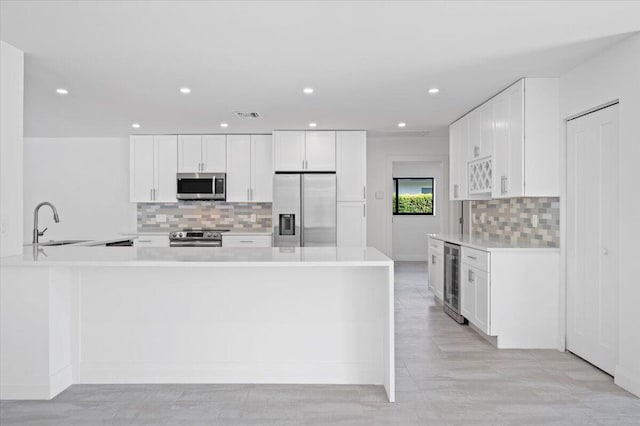 kitchen with backsplash, kitchen peninsula, white cabinets, and stainless steel appliances