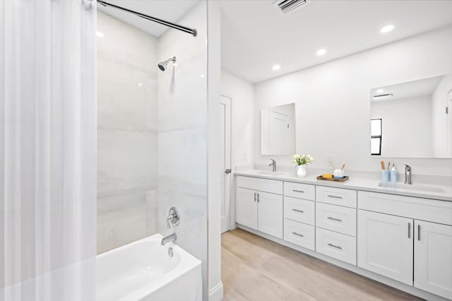 bathroom featuring vanity, hardwood / wood-style floors, and tiled shower / bath combo