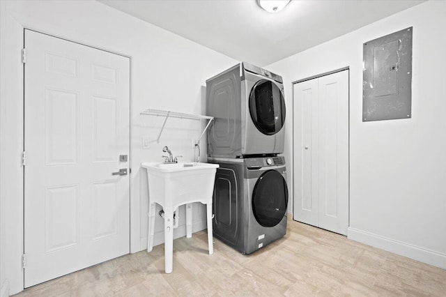 laundry room with light wood-type flooring, electric panel, and stacked washing maching and dryer