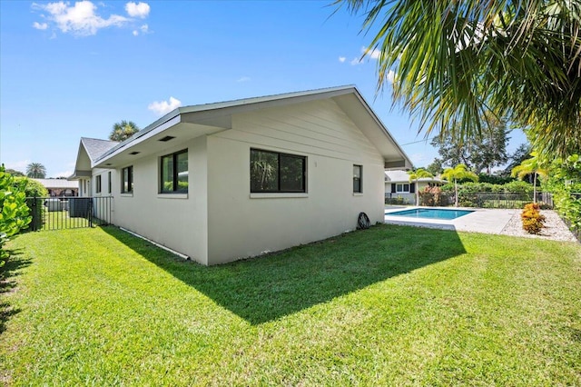 rear view of house featuring a fenced in pool and a yard