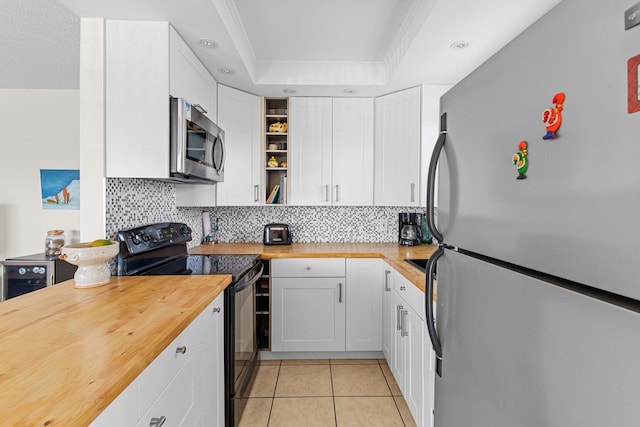 kitchen featuring a raised ceiling, appliances with stainless steel finishes, white cabinetry, and backsplash