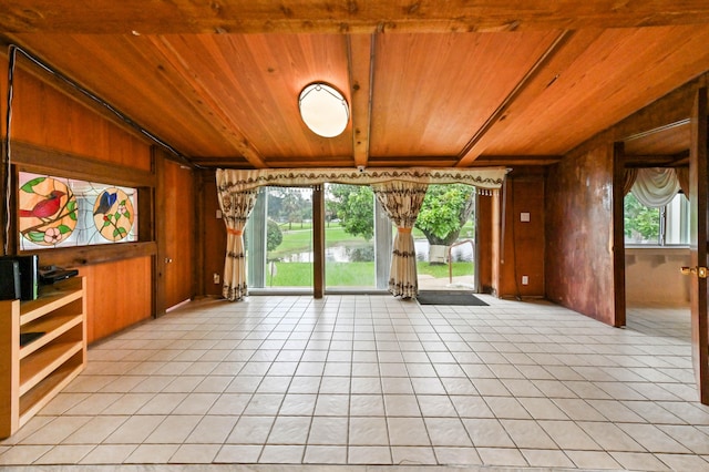 unfurnished living room featuring wood walls, a healthy amount of sunlight, and wooden ceiling