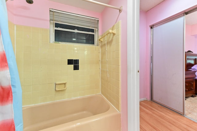 bathroom with hardwood / wood-style flooring and shower / bathtub combination with curtain