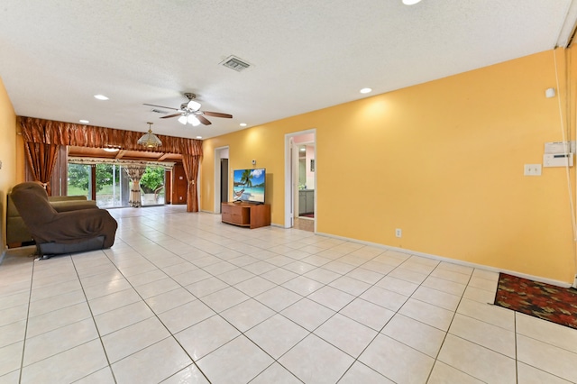 unfurnished living room with wooden walls, a textured ceiling, light tile patterned floors, and ceiling fan