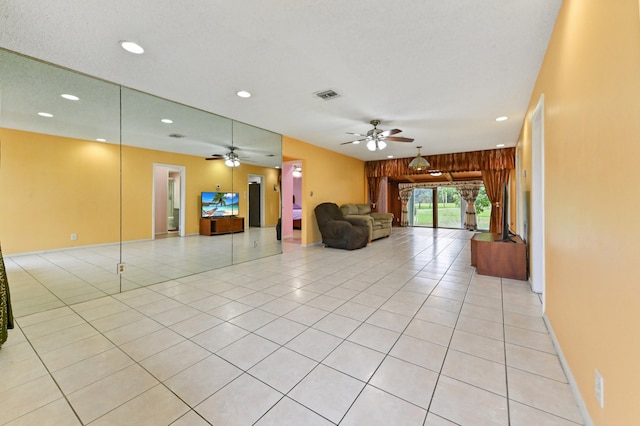 unfurnished living room with ceiling fan, a textured ceiling, light tile patterned floors, and wooden walls