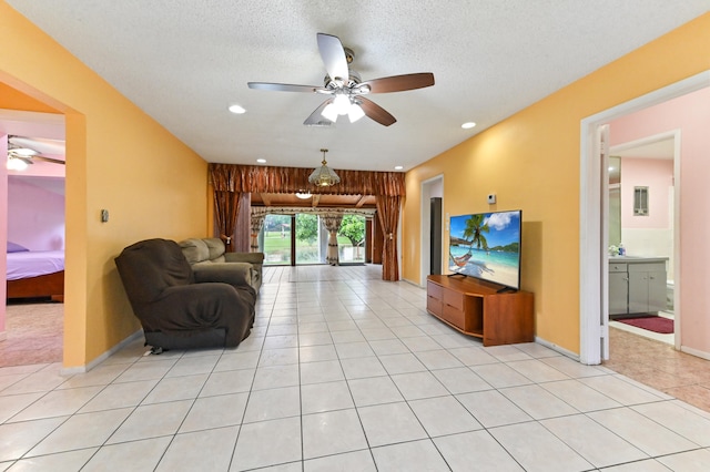 living room featuring light tile patterned flooring, a textured ceiling, and ceiling fan