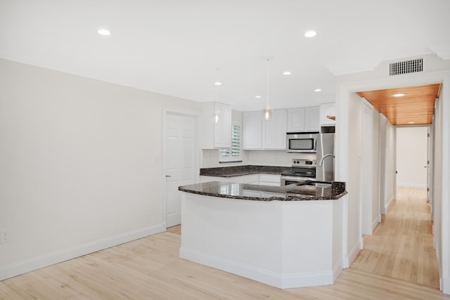 kitchen with white cabinetry, light hardwood / wood-style flooring, dark stone counters, stainless steel appliances, and decorative light fixtures