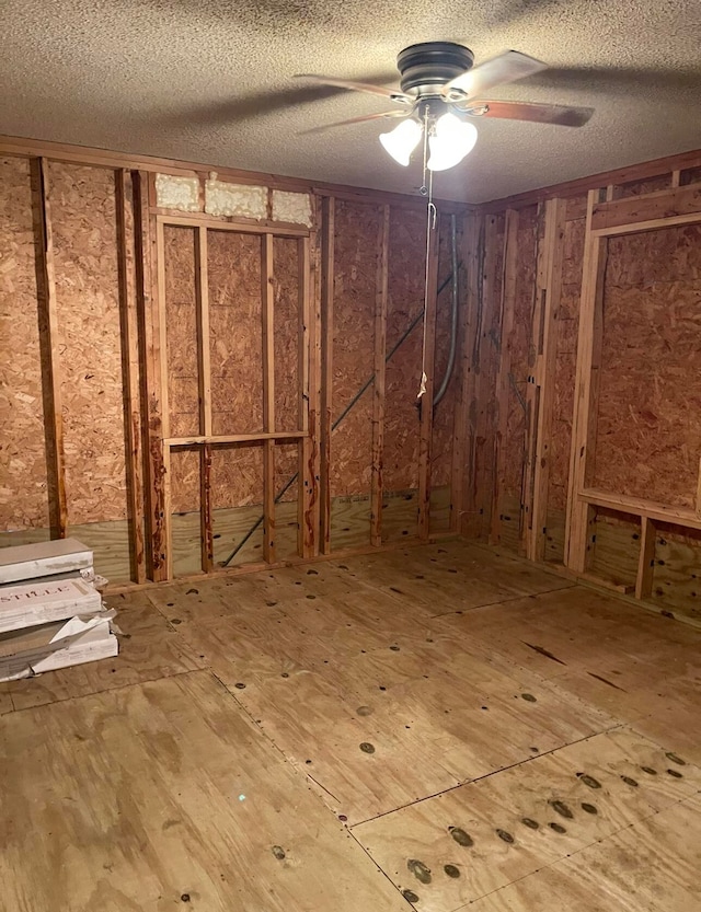 basement featuring ceiling fan and a textured ceiling