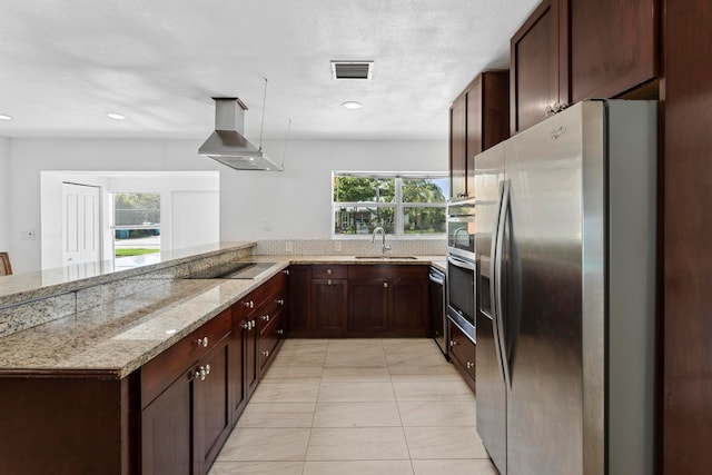 kitchen featuring appliances with stainless steel finishes, kitchen peninsula, wall chimney exhaust hood, light tile patterned floors, and sink