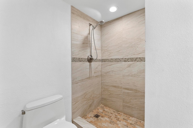 bathroom featuring tiled shower and toilet