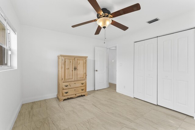 unfurnished bedroom featuring ceiling fan, light tile patterned floors, and a closet