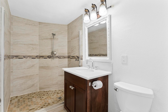 bathroom featuring vanity, a tile shower, and toilet