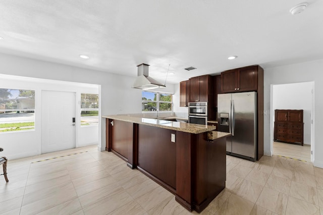 kitchen with island exhaust hood, appliances with stainless steel finishes, stone counters, light tile patterned floors, and kitchen peninsula