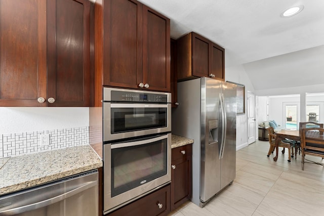 kitchen with stainless steel appliances, light stone countertops, light tile patterned floors, decorative backsplash, and vaulted ceiling