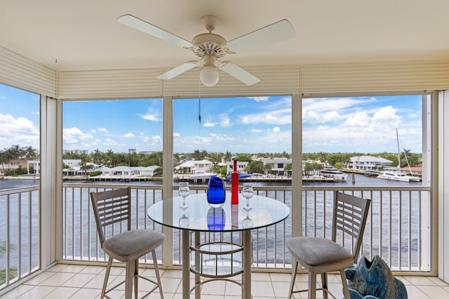 sunroom featuring ceiling fan, a water view, and a wealth of natural light