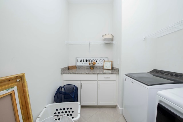 clothes washing area featuring washing machine and dryer, light tile patterned floors, and cabinets