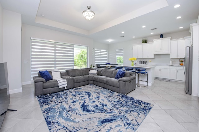 tiled living room featuring a tray ceiling