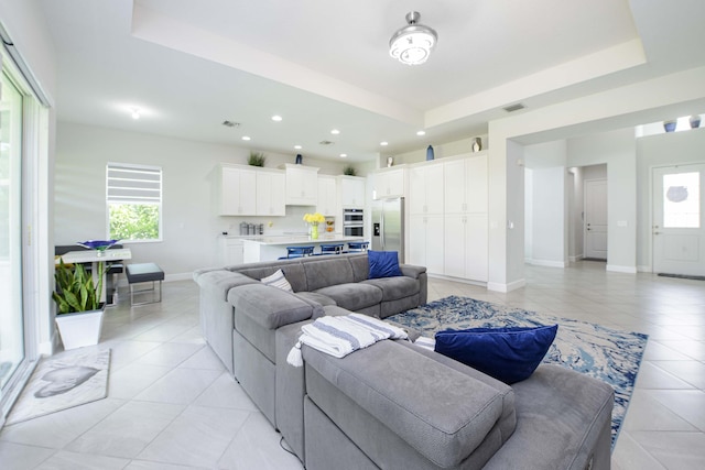 living room featuring light tile patterned flooring, a healthy amount of sunlight, and a tray ceiling