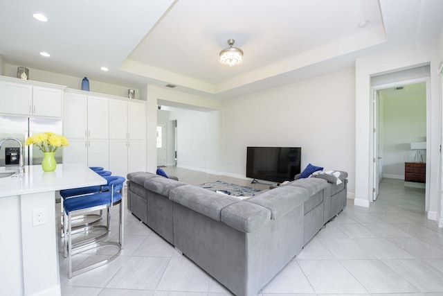 living room with light tile patterned flooring and a raised ceiling