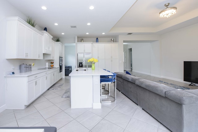 kitchen featuring appliances with stainless steel finishes, a kitchen bar, an island with sink, and white cabinets