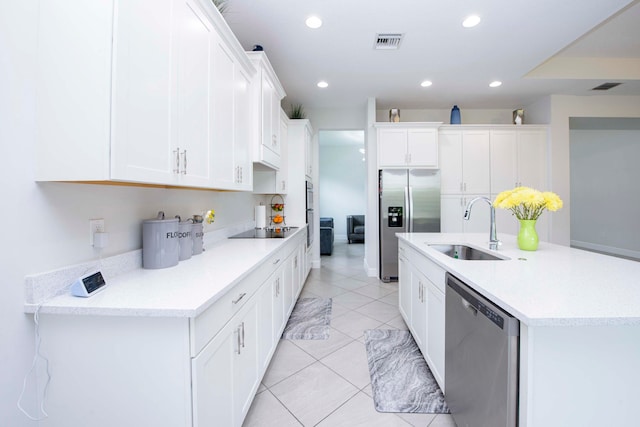 kitchen with stainless steel appliances, an island with sink, white cabinets, light tile patterned floors, and sink