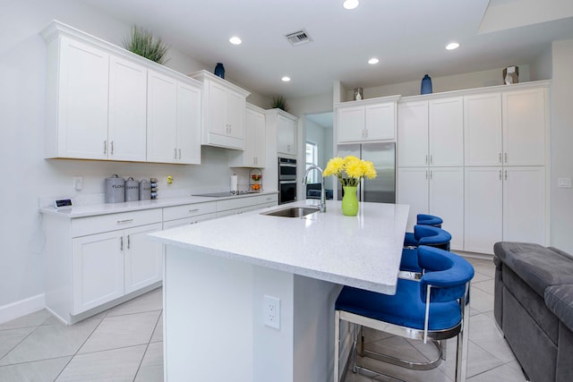 kitchen with white cabinets, sink, a breakfast bar, and light tile patterned floors